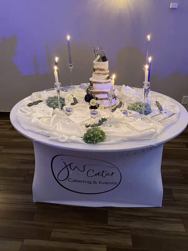 Wedding cake table with tall candles and greenery