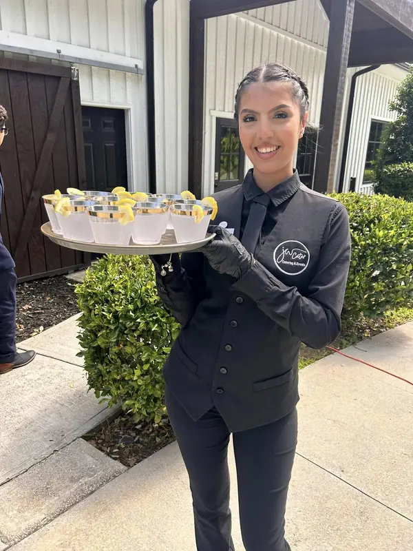 JW Cater server holding a tray of dessert cups