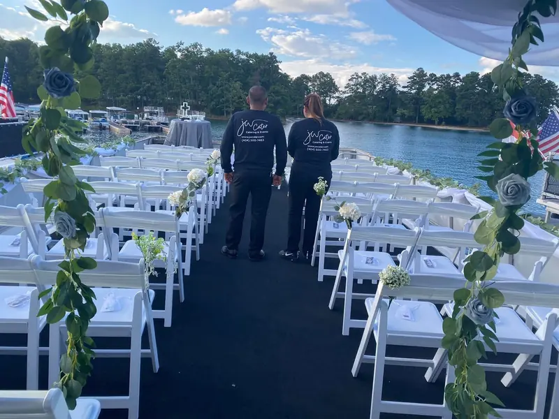 JW Cater staff on a lakeside dock ceremony aisle lined with greenery