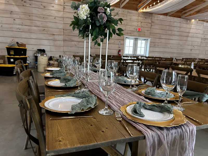 Farm table with gold chargers, pink runner and tall florals