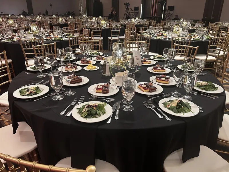 Black linen gala tables with plated dinner and salads