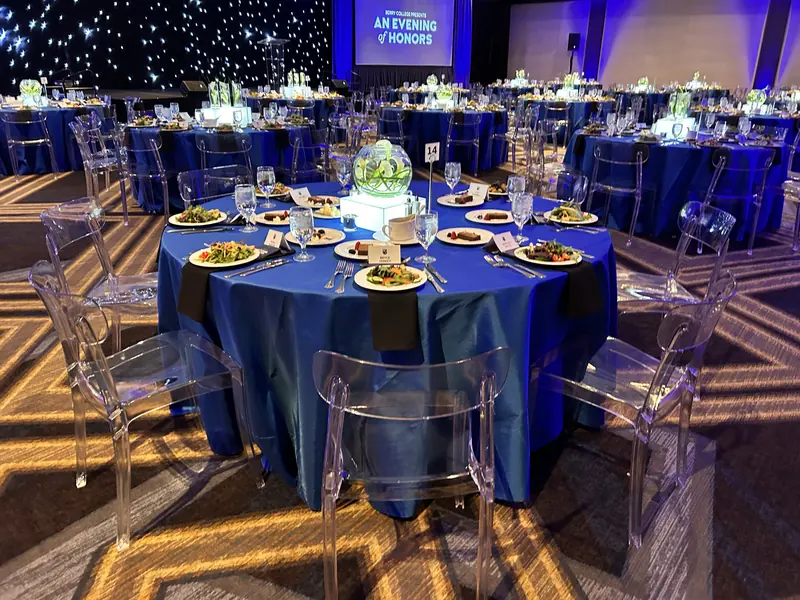 Gala dinner tables in navy with plated meals and glowing centerpieces