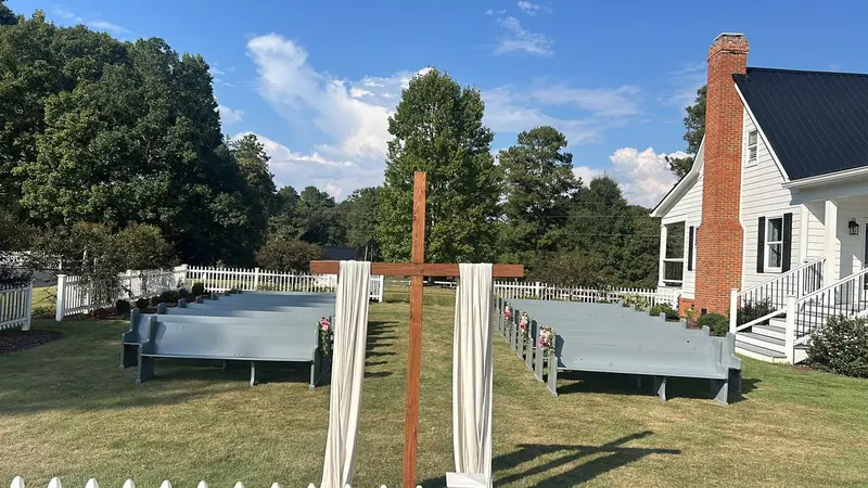 Garden ceremony with a wooden cross, draped fabric and benches