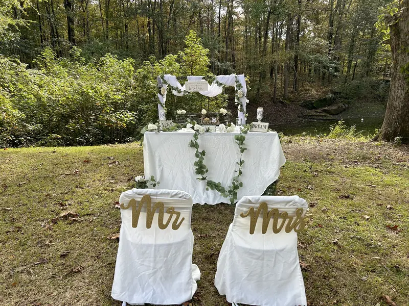 Garden sweetheart table with Mr and Mrs chair signs under a draped arch