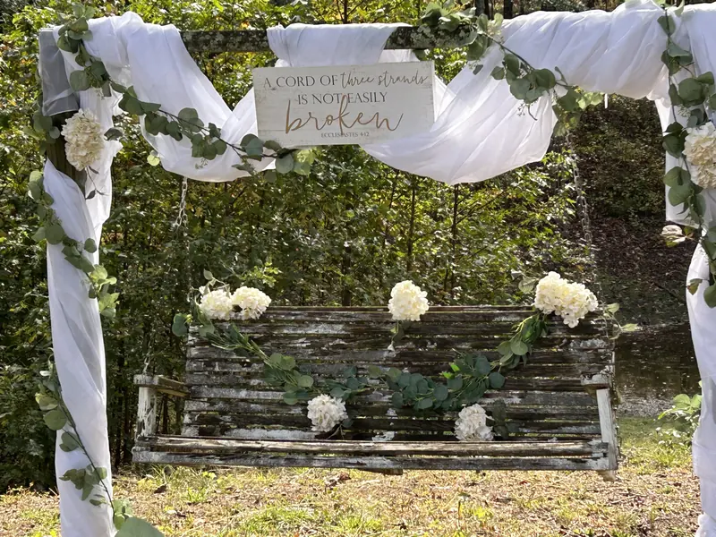 Rustic swing decorated with white flowers and draped fabric