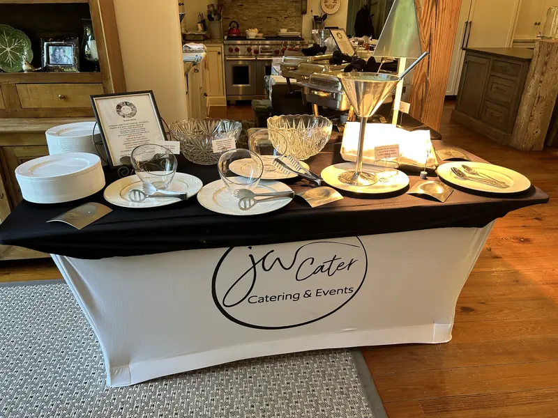 Buffet in a home kitchen with plates and glassware on a JW Cater cover
