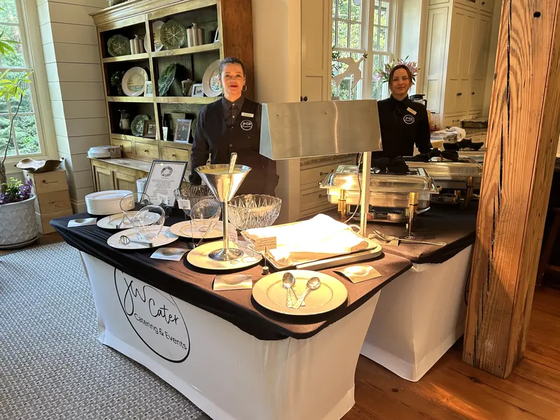 Two JW Cater staff serving a buffet at a home event