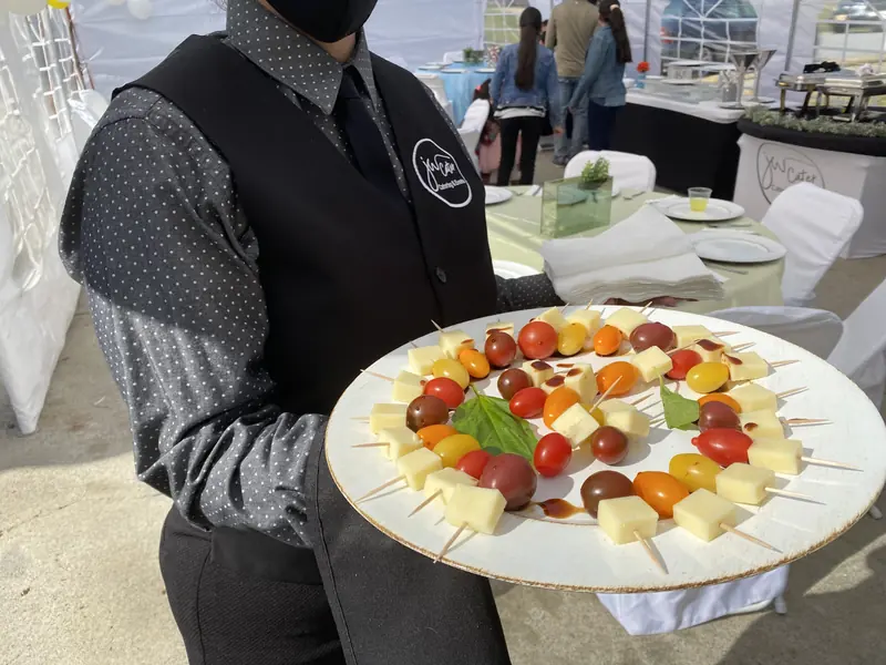 Server holding a platter of fruit and cheese bites