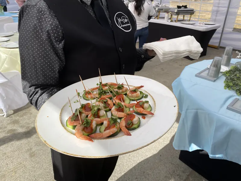 Server carrying a platter of shrimp appetizers