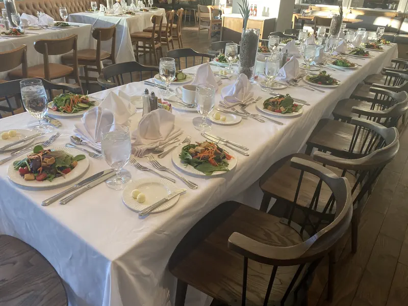 Long table set with plated salads and folded napkins