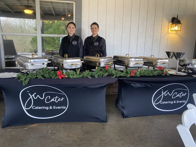 Two JW Cater staff behind a holiday porch buffet