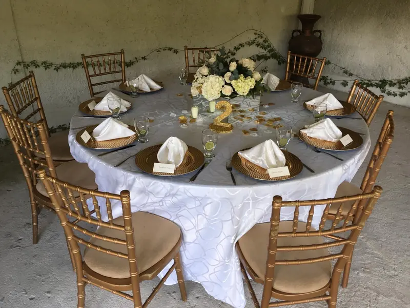 Round table with gold chairs and folded napkins