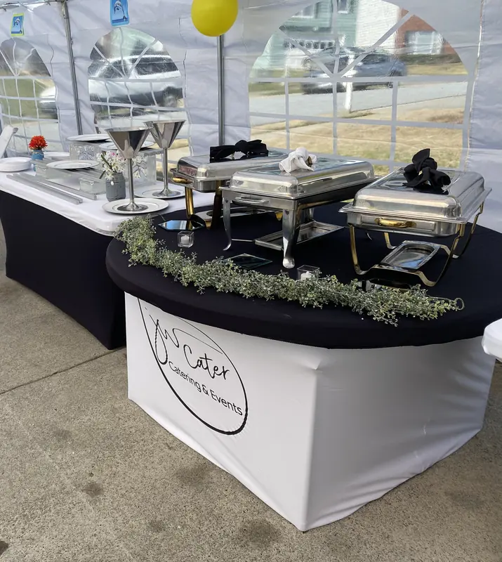 Buffet under a tent with chafers and a round JW Cater table
