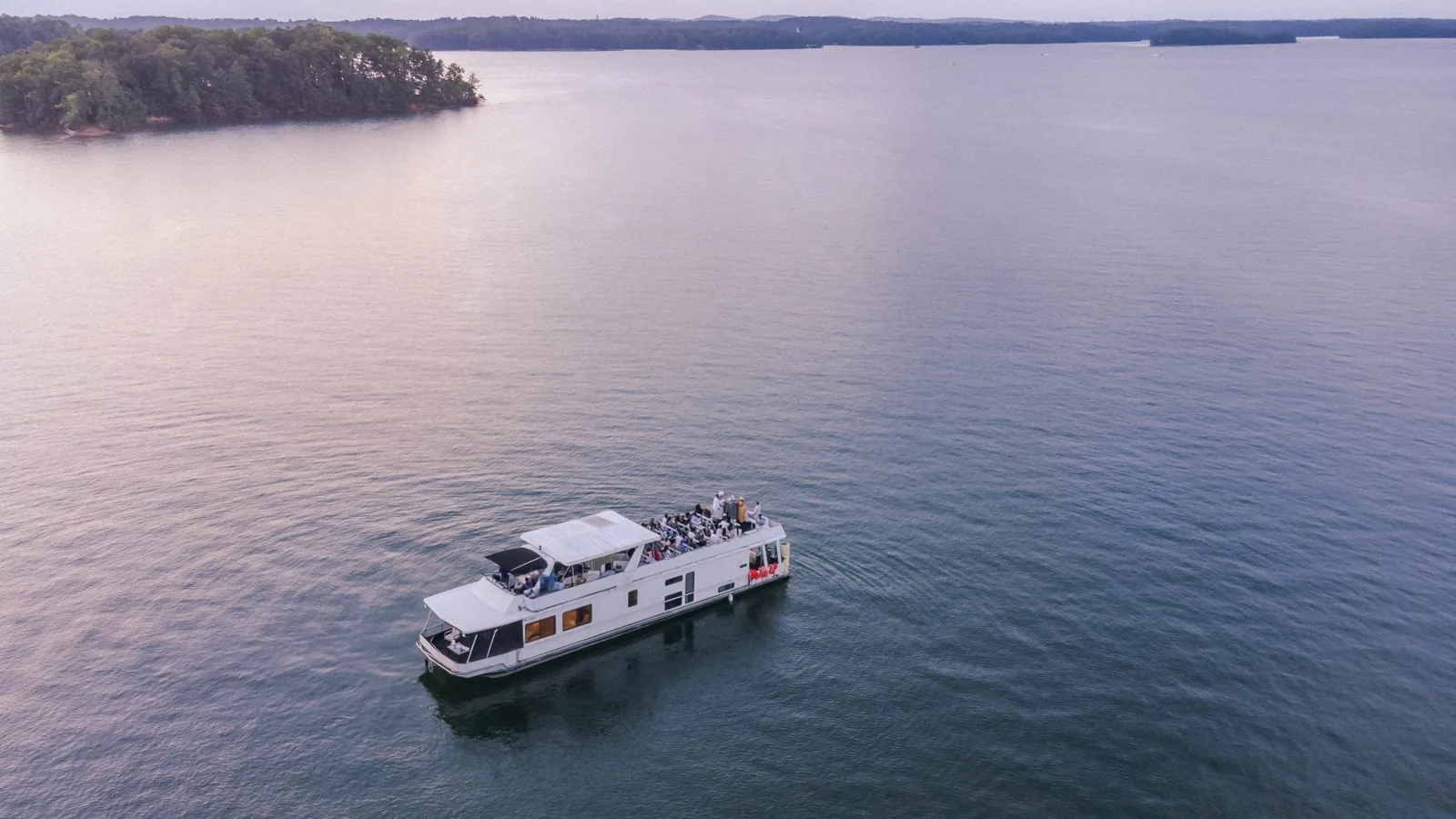 Aerial view of a houseboat wedding party on a lake at sunset