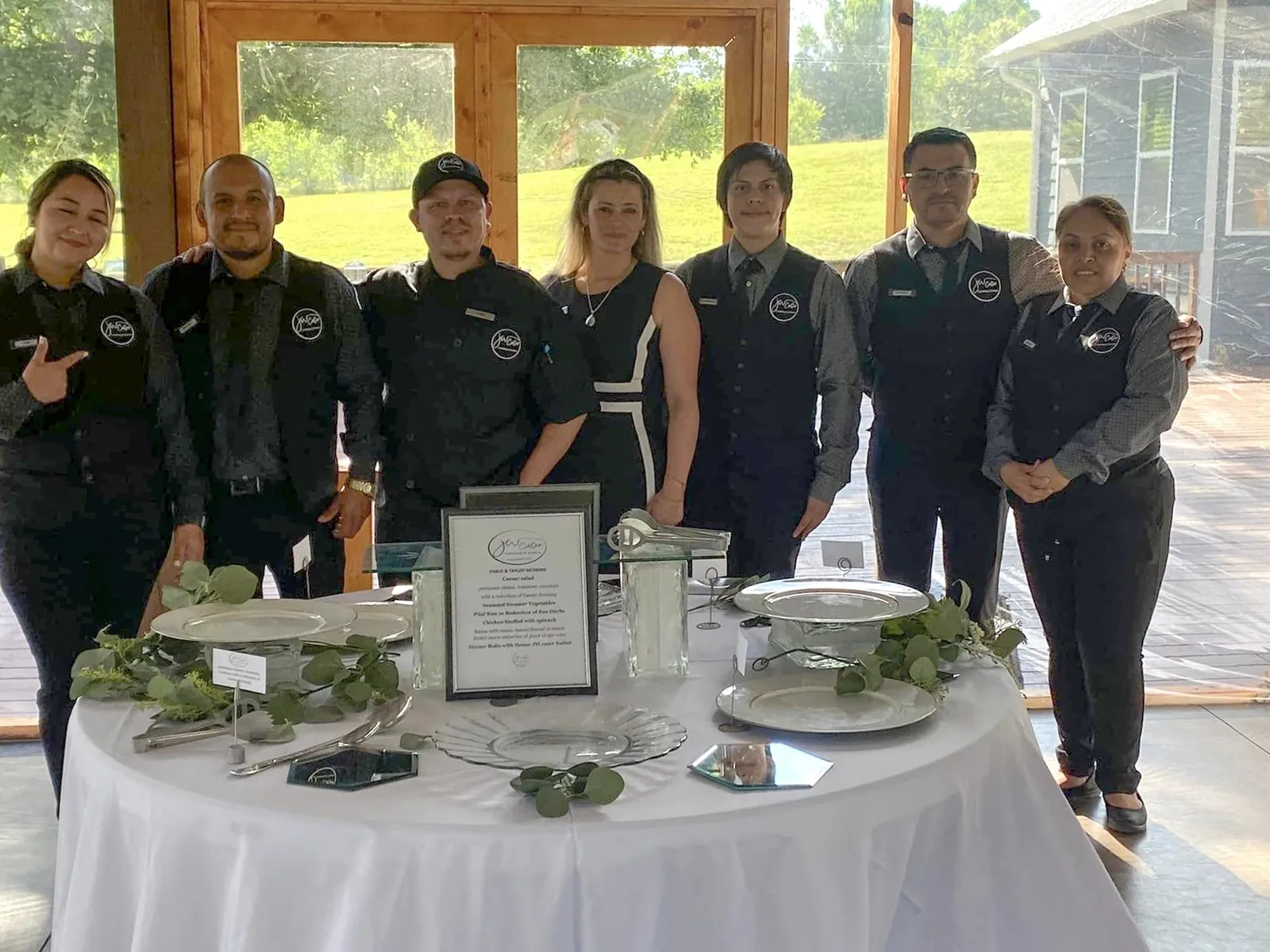 The JW Cater team in black uniforms beside a set table in an open pavilion