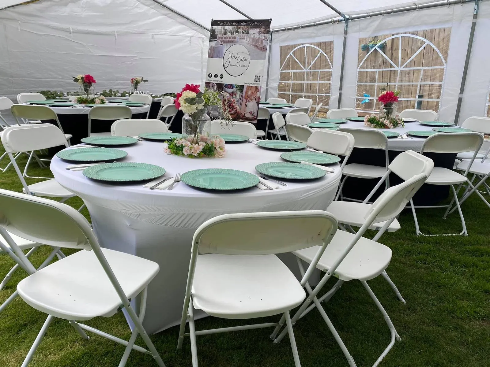 White tent with round tables, green plates and floral centerpieces